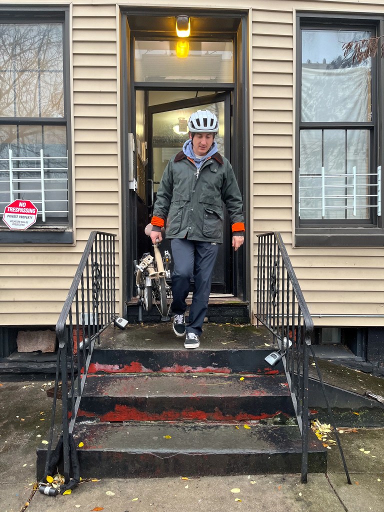 a man walking out of a building carrying a folded bike