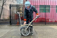 a man folding up a brompton c line explore bike on a sidewalk