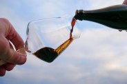 a beer being poured from a bottle into a teku glass