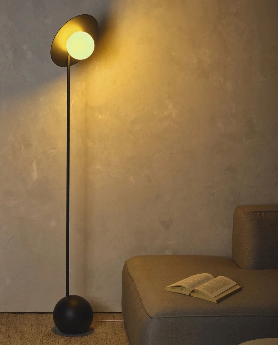 a floor lamp next to a couch with an open book