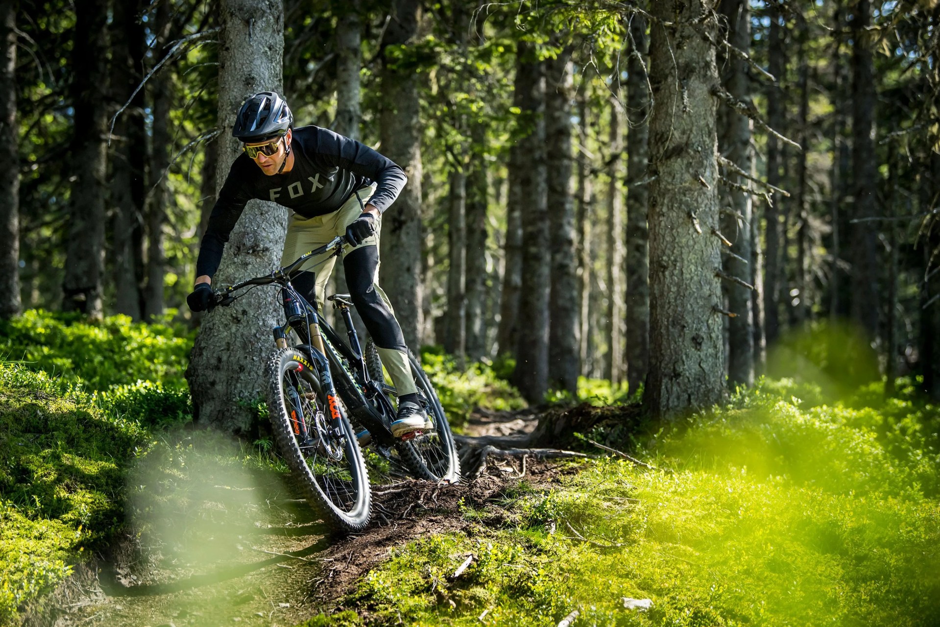 rox racing man riding bike through forrest wearing speedframe pro mountain bike helmet