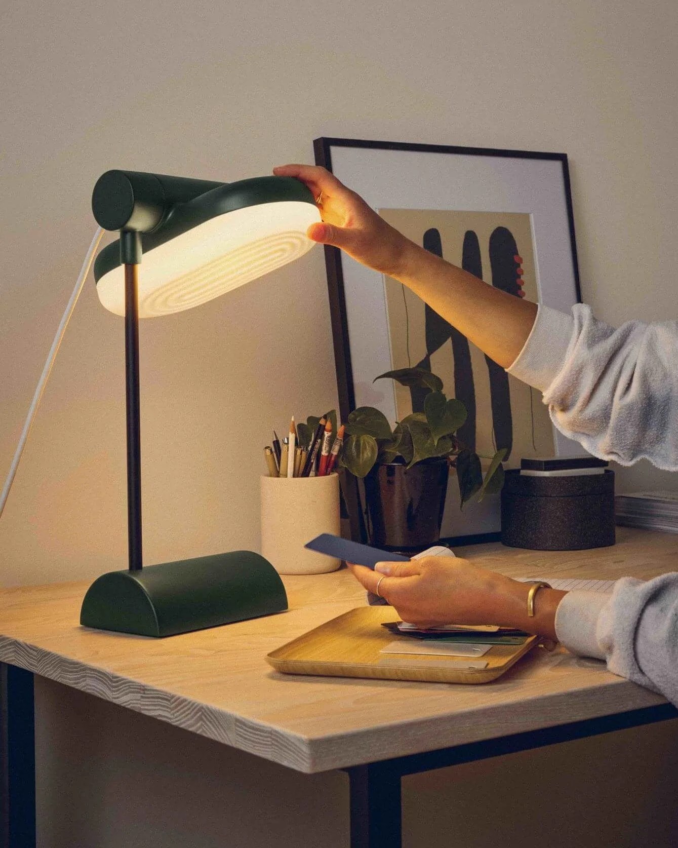 a woman sitting at a desk reading with a desk lamp