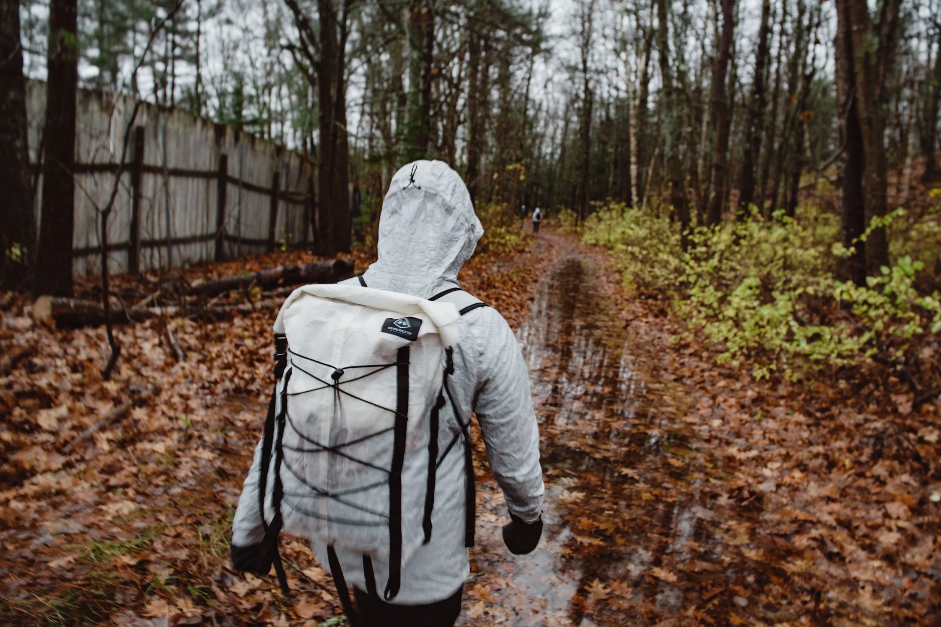 a person walking through the woods in the rain wearing a rain coat and backpack
