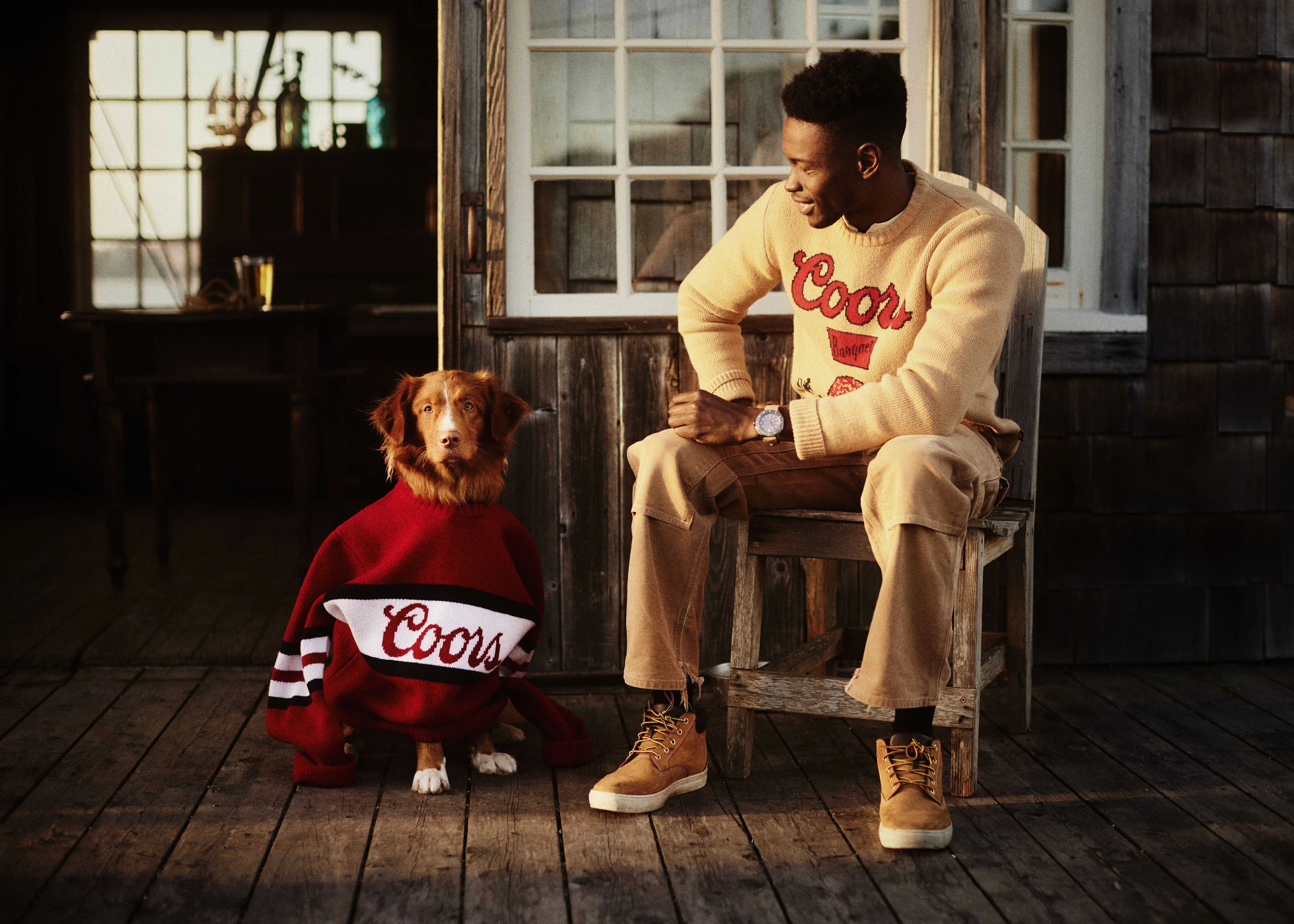 huckberry man wearing coors sweater sitting next to dog wearing a coors sweater