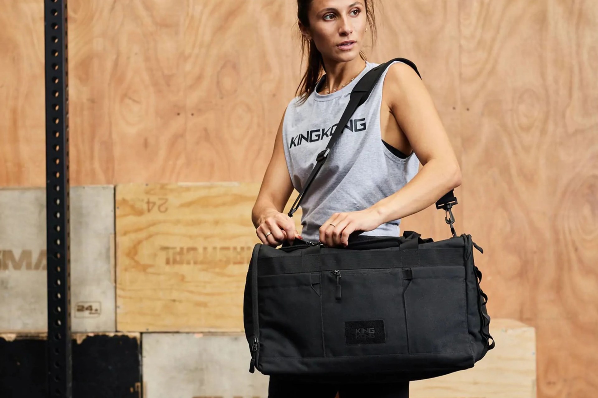 a woman at a gym carrying a black duffel bag