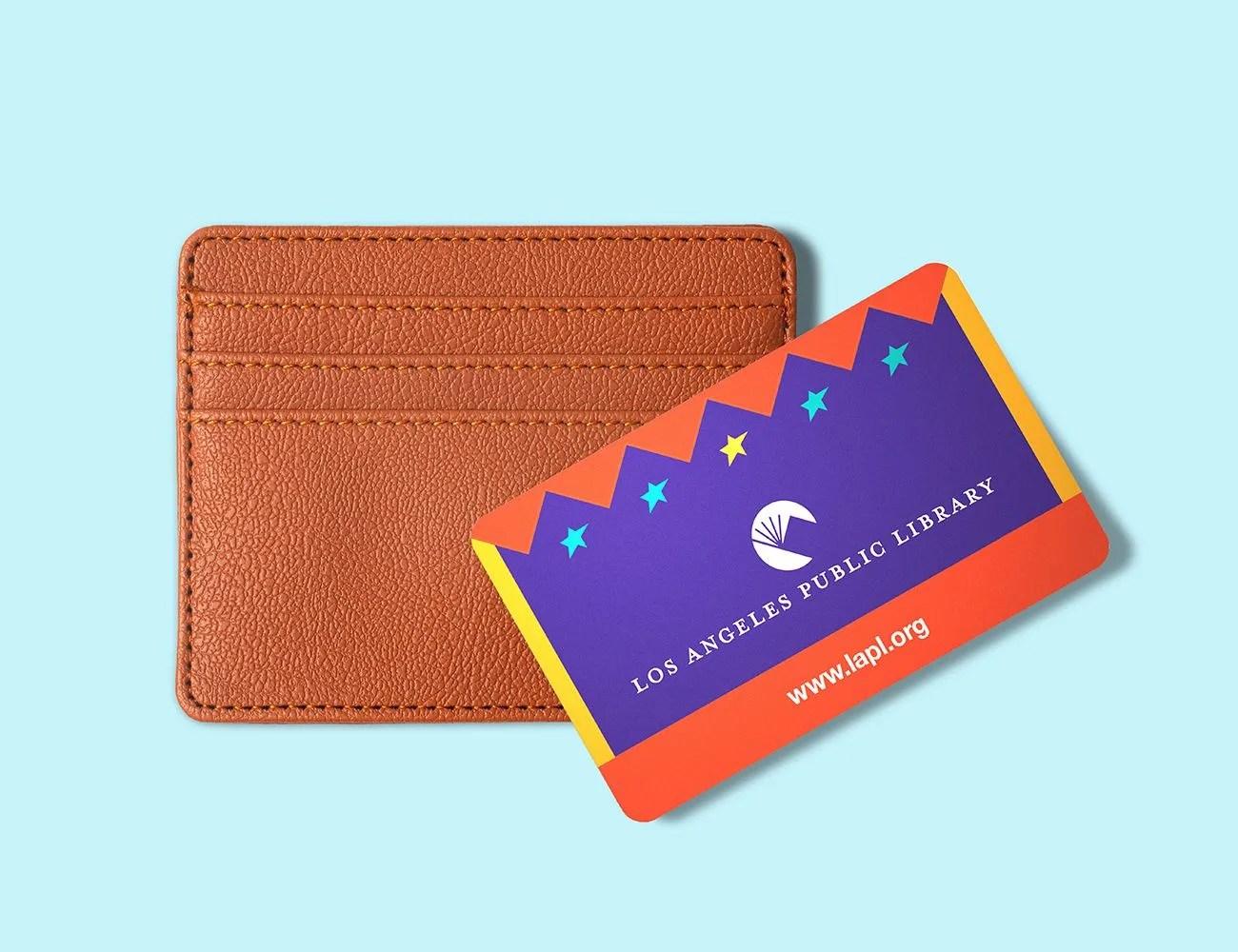 a los angeles public library card laying on top of a brown leather wallet