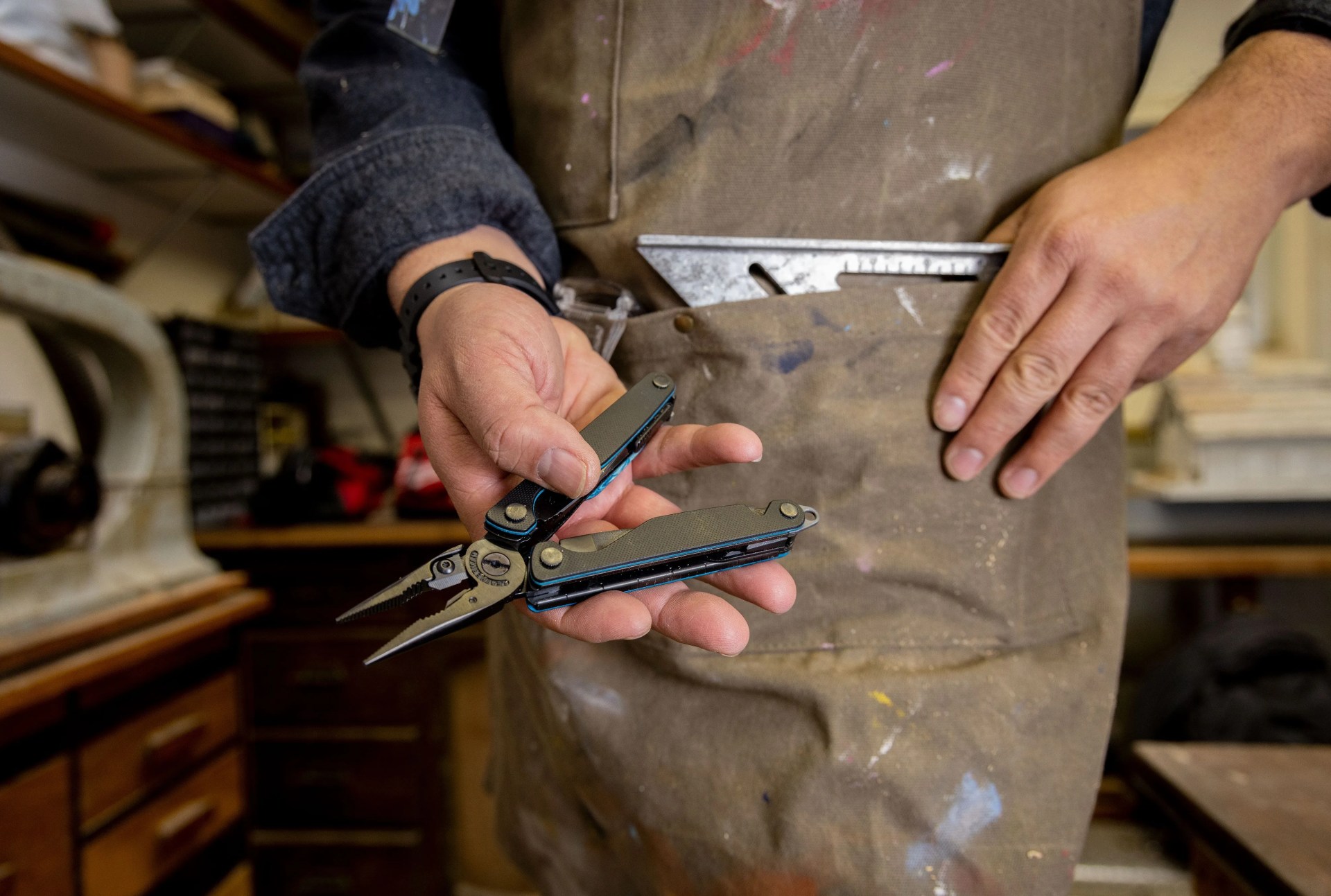 man holding leatherman tool in workshop