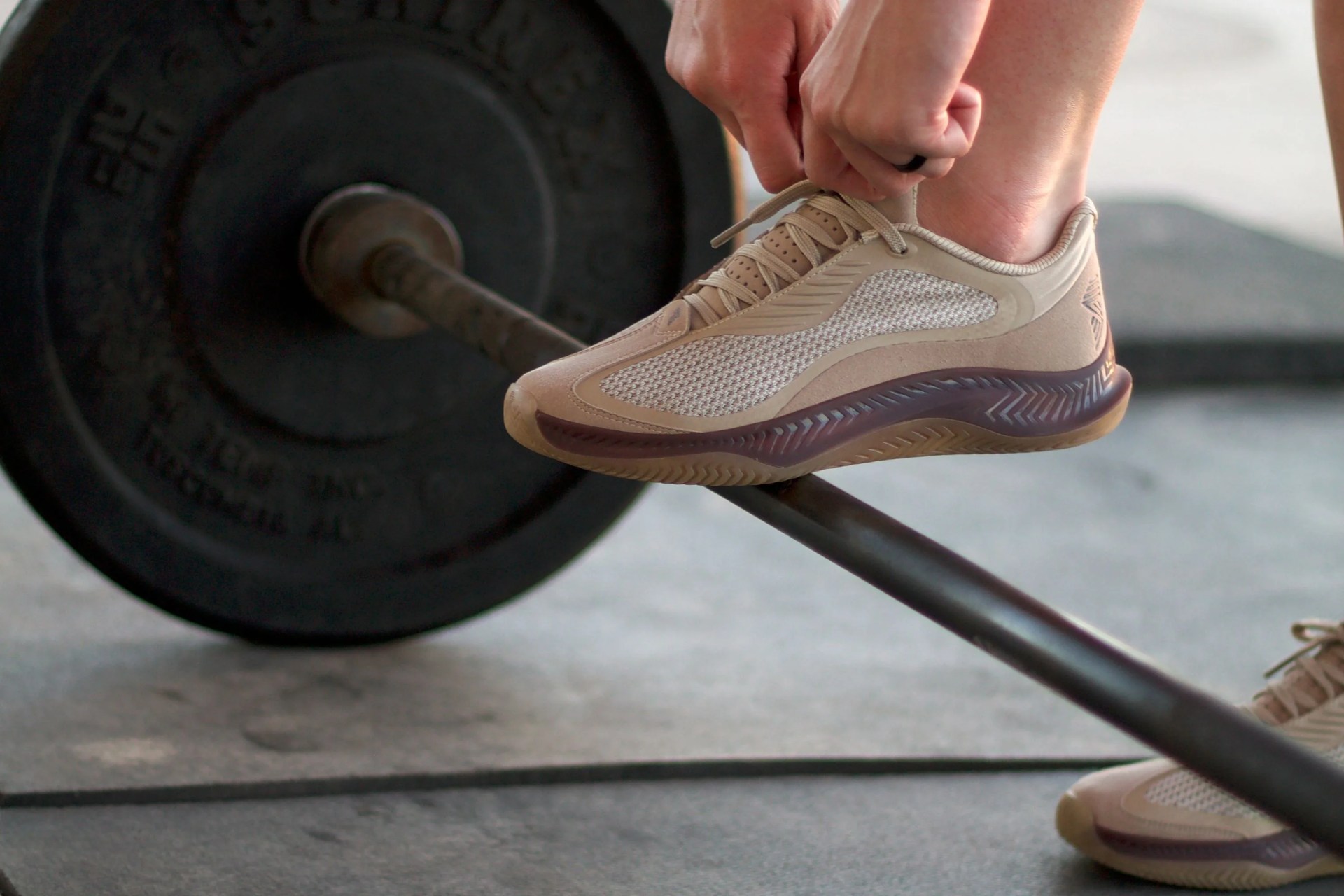 woman tying her shoe with foot on a benchpress bar