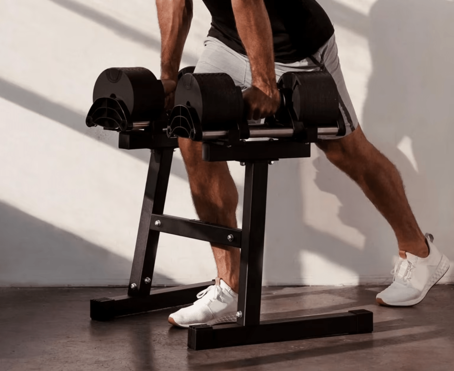 person picking up dumbbells from a stand