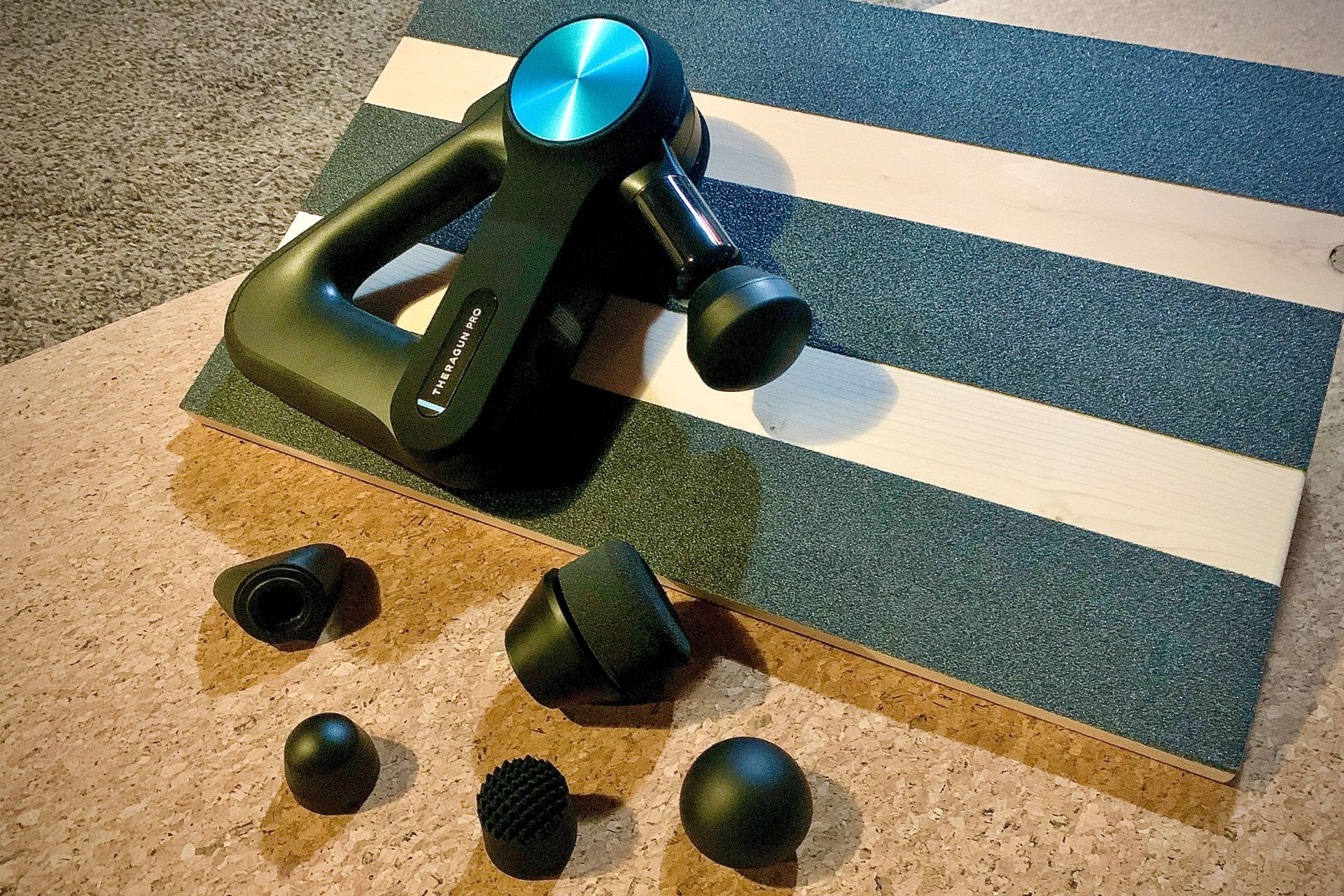 a therabody pro massage gun and extra massage heads sitting on a work out wedge and yoga mat