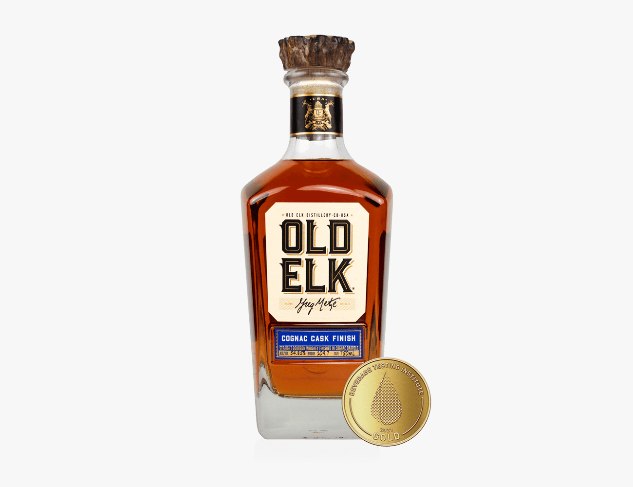 A glass bottle with brown liquor and a white gold and black label
