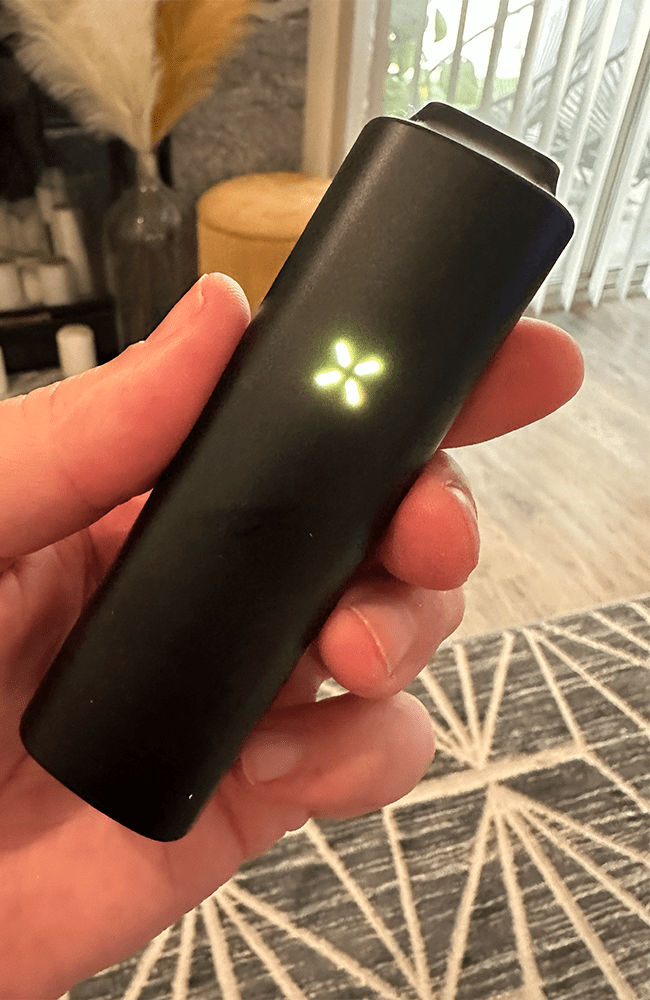a hand holding a black pax plus showing a green light on the front