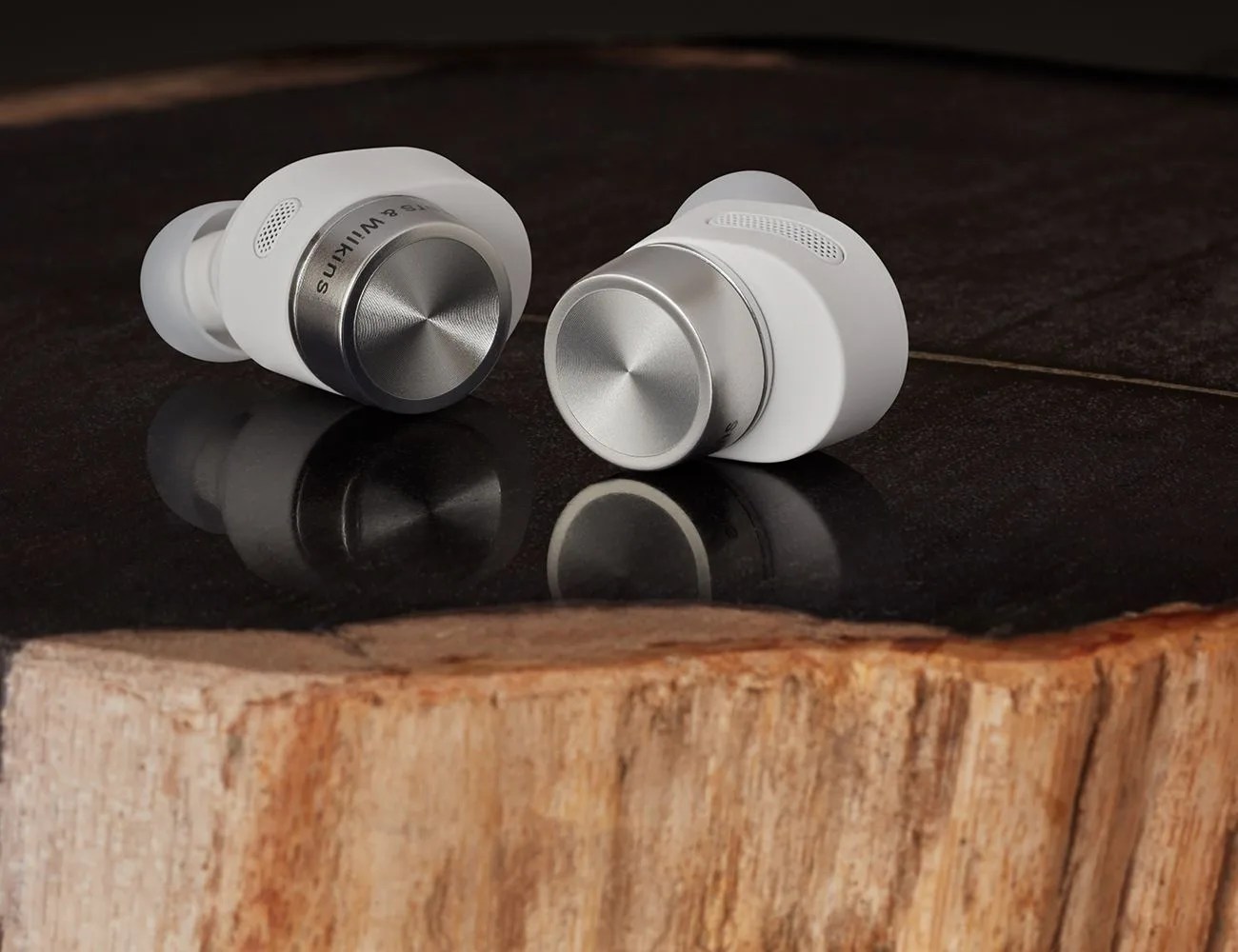 white wireless earbud headphones resting on a wood table