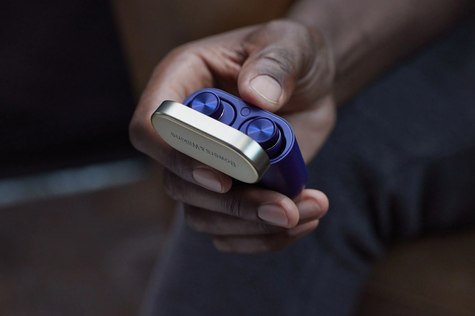 a hand holding a blue earbud case flipped open with blue earbuds inside