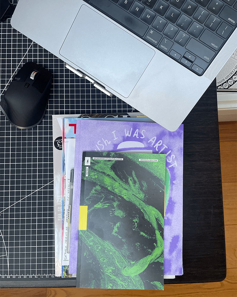 multiple magazines stacked ontop of a black desk