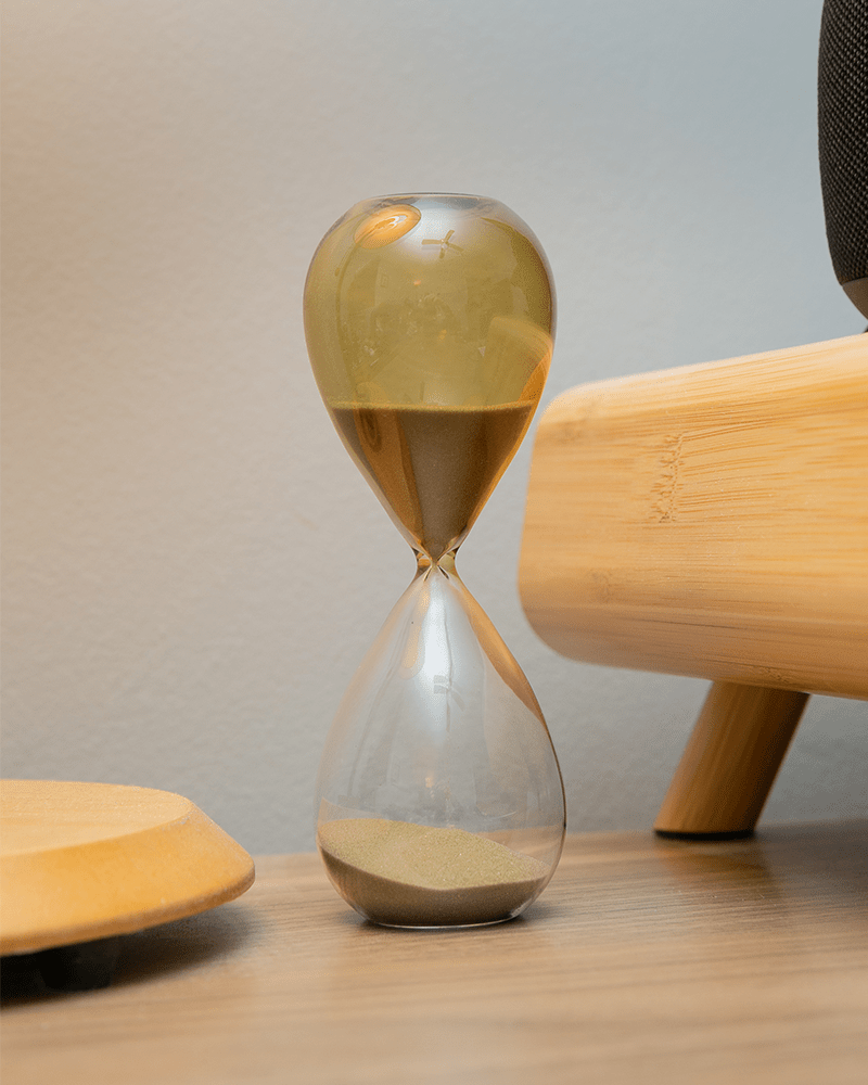 an hourglass on light brown desk