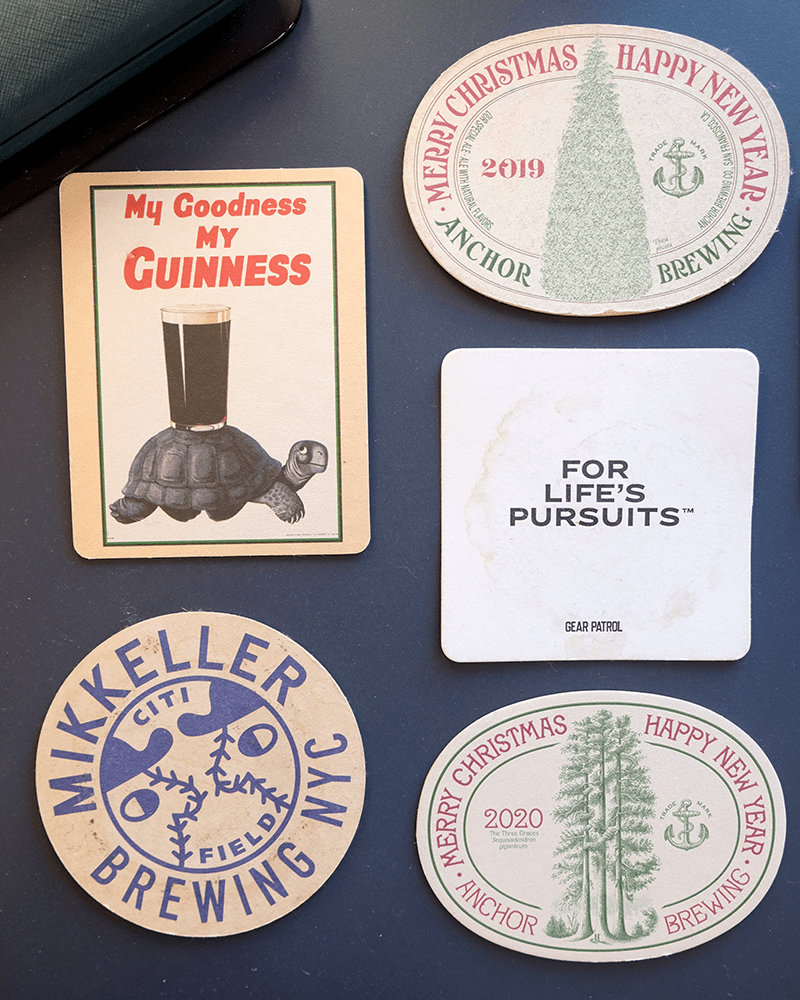 a navy desk pad underneath 5 different beer coasters