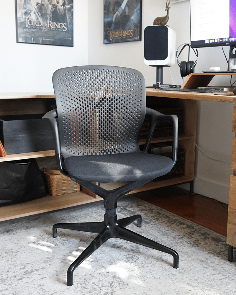 a black desk chair in front of a light brown wood desk