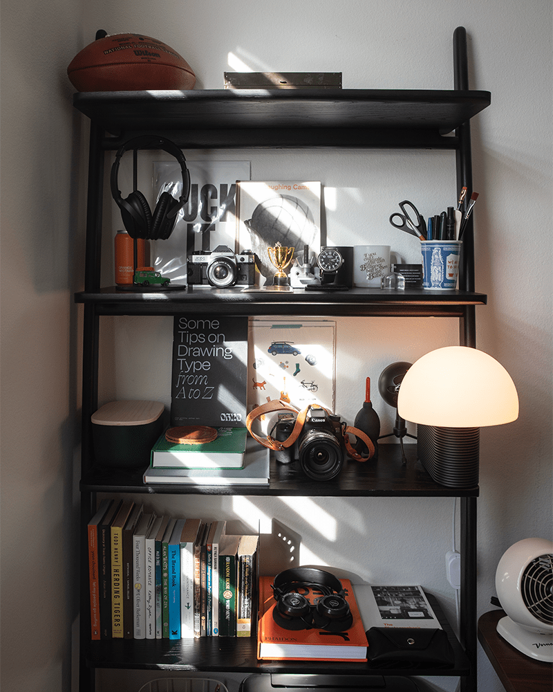 a close up photo of a black bookshelf with multiple books and other assorted items