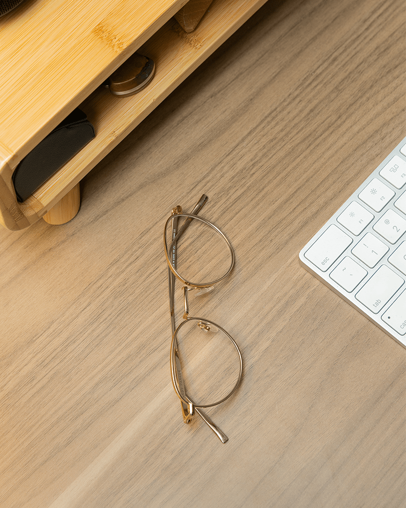 gold warby parker ezra glasses on a light brown desk