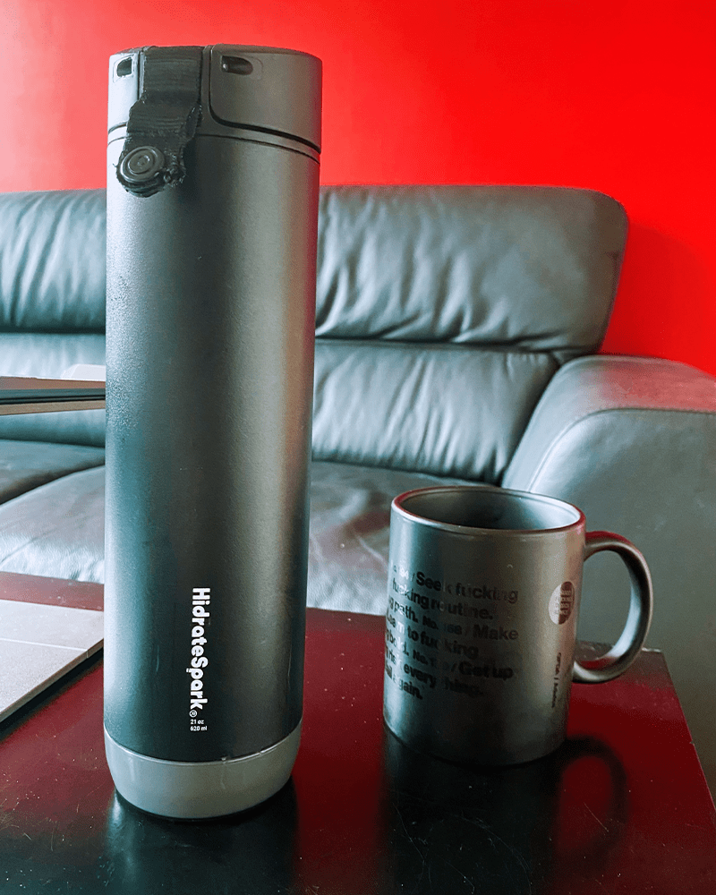 a black water bottle and a black coffee mug on a black table