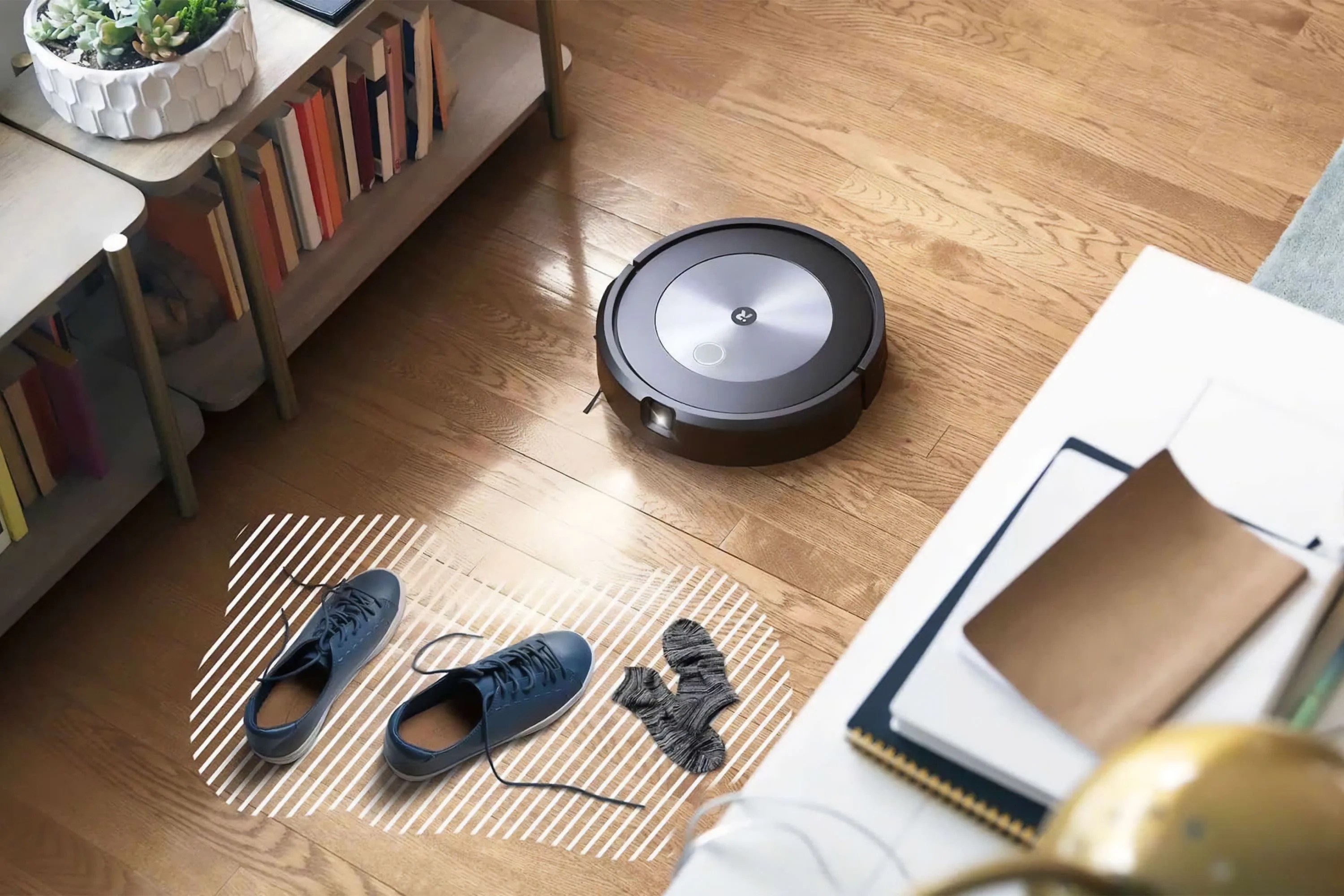 a roomba vacuum cleaner on a wood floor next to a pair of shoes and socks