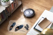 a roomba vacuum cleaner on a wood floor next to a pair of shoes and socks