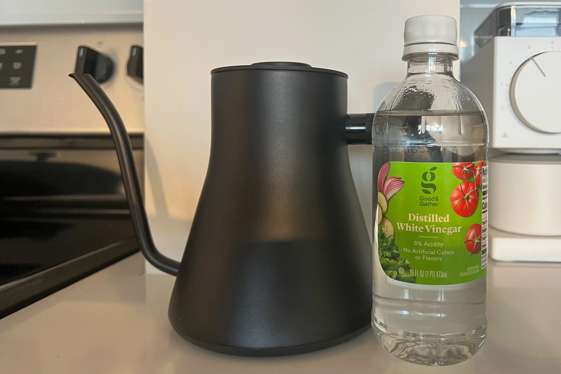 an electric kettle on a counter next to a bottle of vinegar