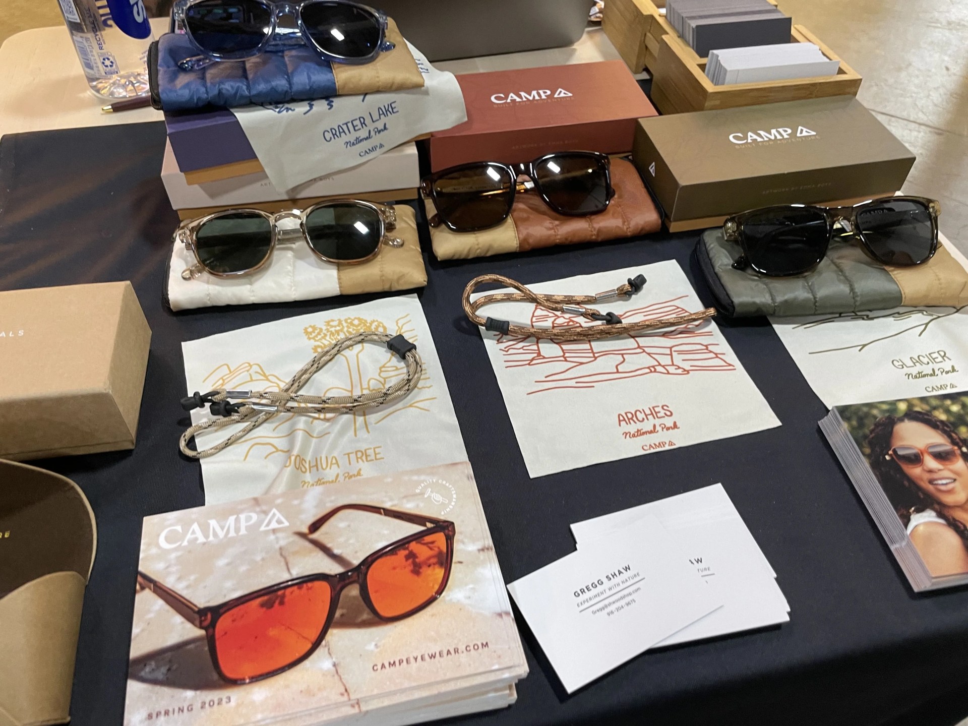 a variety of sunglasses on a table with boxes and pamphlets