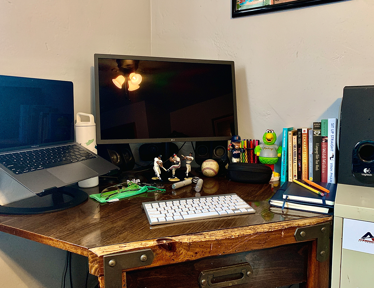 a full view of bens wood desk with computer monitor, laptop, mini figurines, books and keyboard