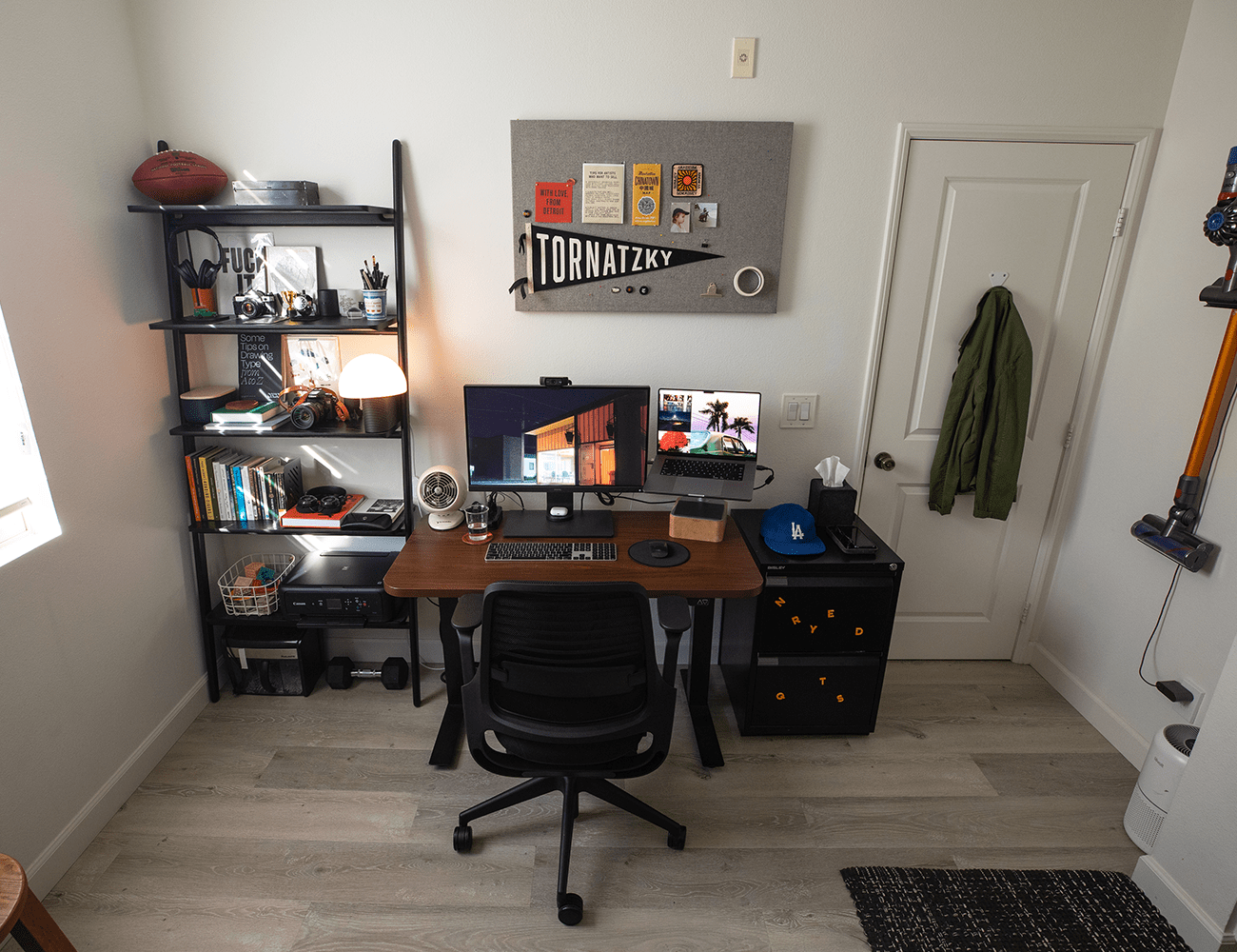 a dark brown desk and black chair in front of a white wall