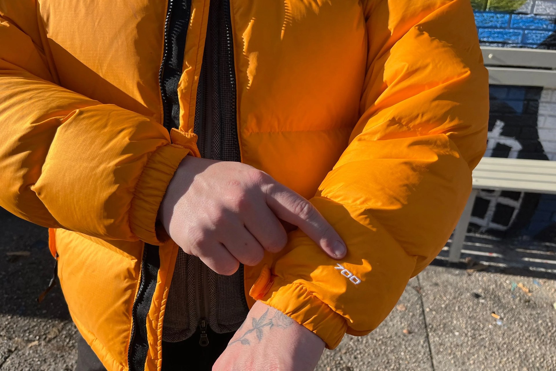 a hand pointing to a sleeve on a zip up puffer jacket