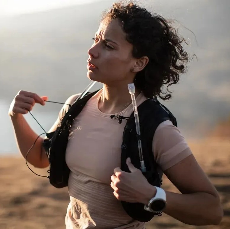 woman wearing a hydration vest while taking a break from running