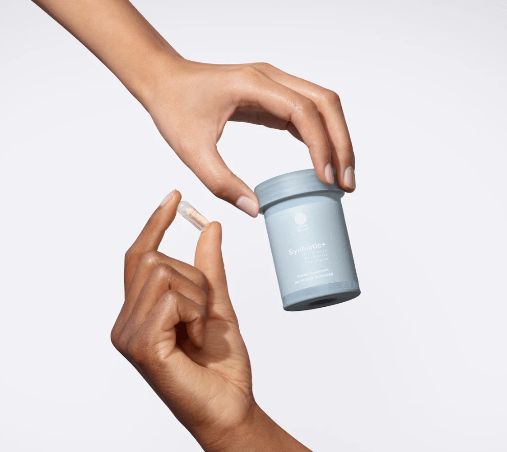two hands holding bottle and pill