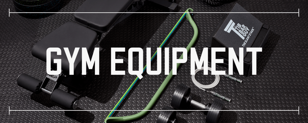 various pieces of gym equipment laid out on black rubber gym flooring with text saying gym equipment laid over top the photo