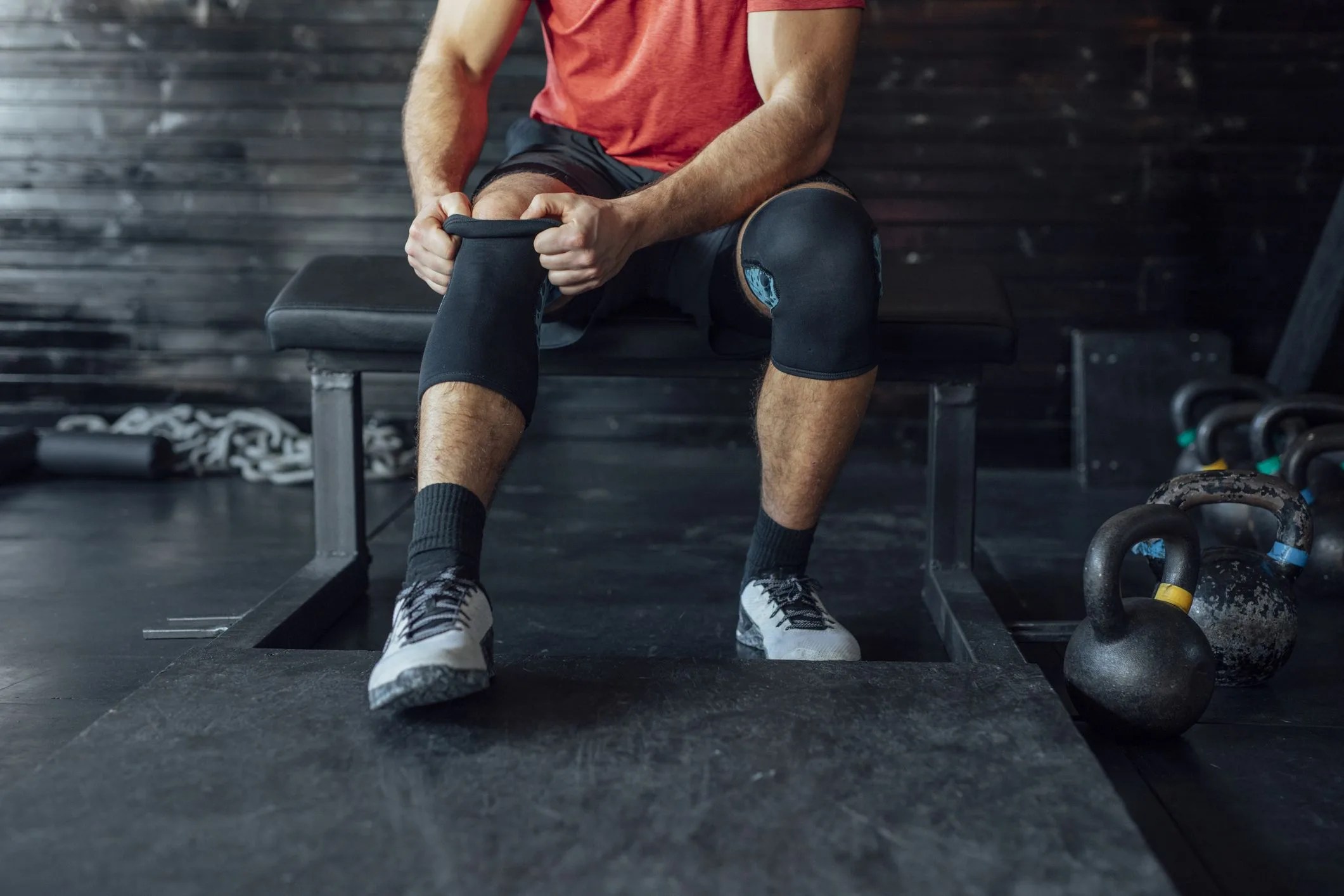 sportsman putting on a knee sleeve at the gym