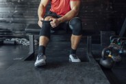 sportsman putting on a knee sleeve at the gym