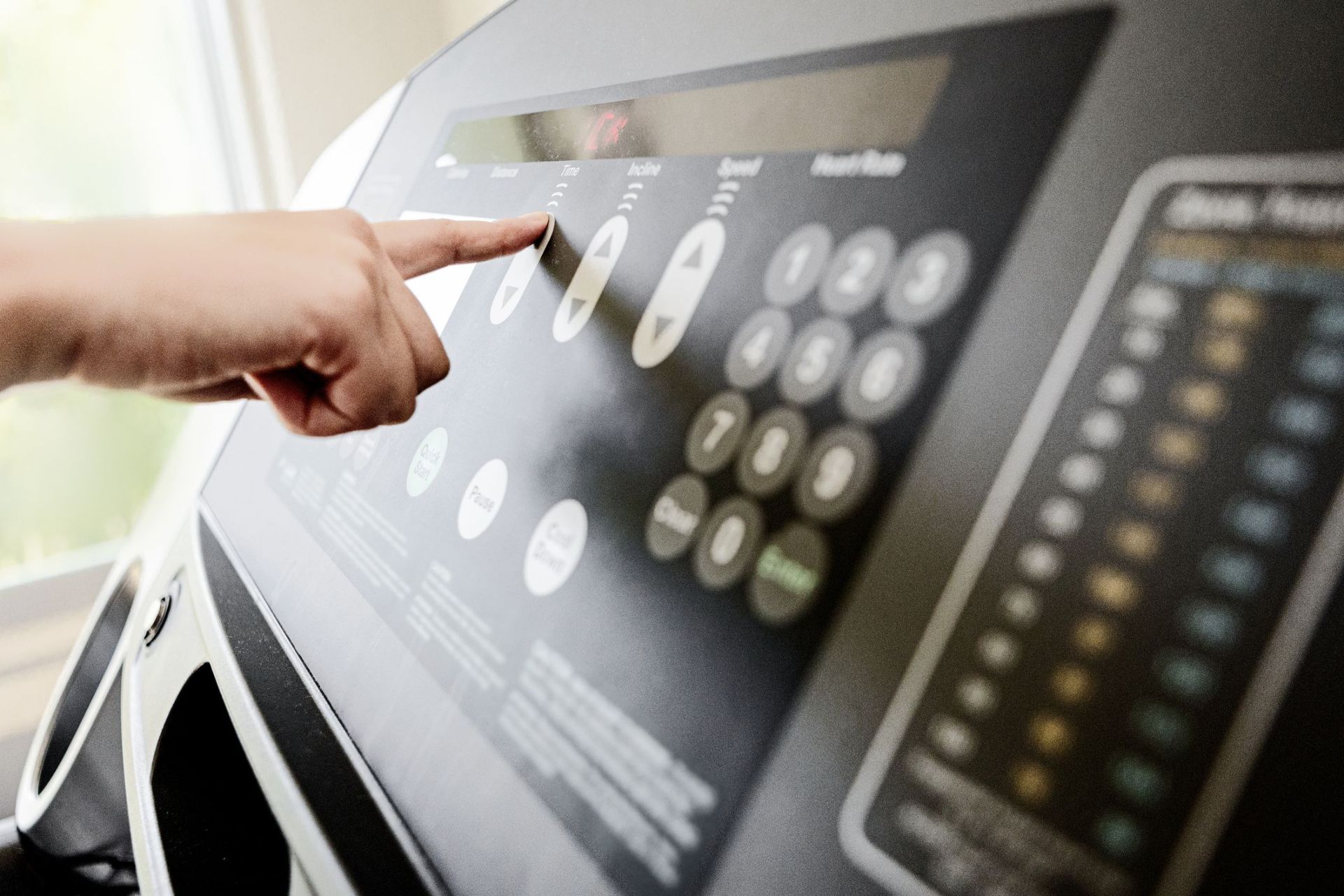 unrecognizable woman adjusting controls on treadmill for running