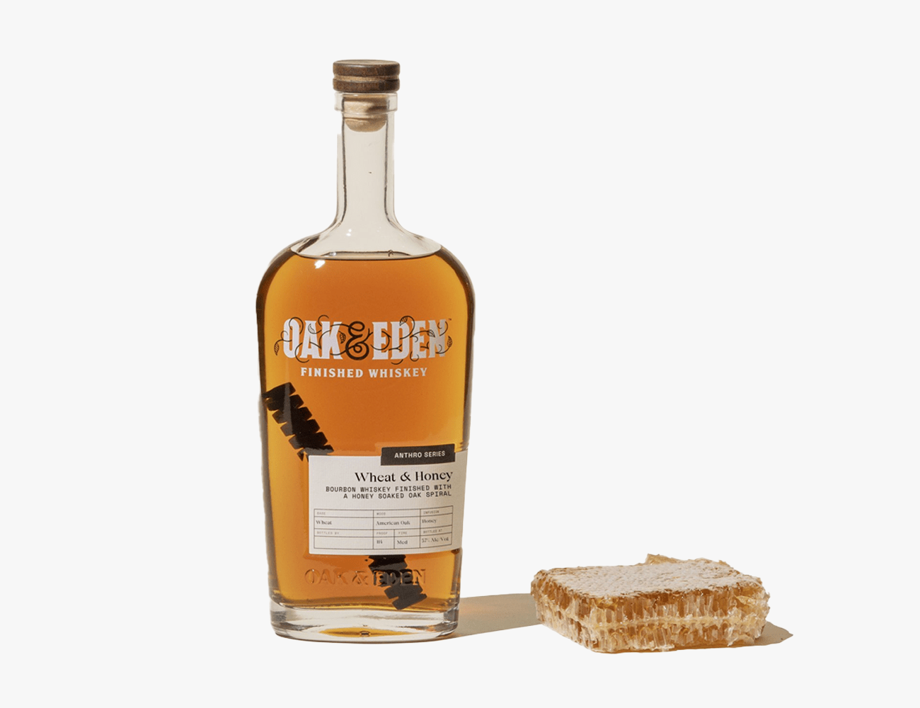 a glass bottle of oak and eden whiskey next to a honeycomb