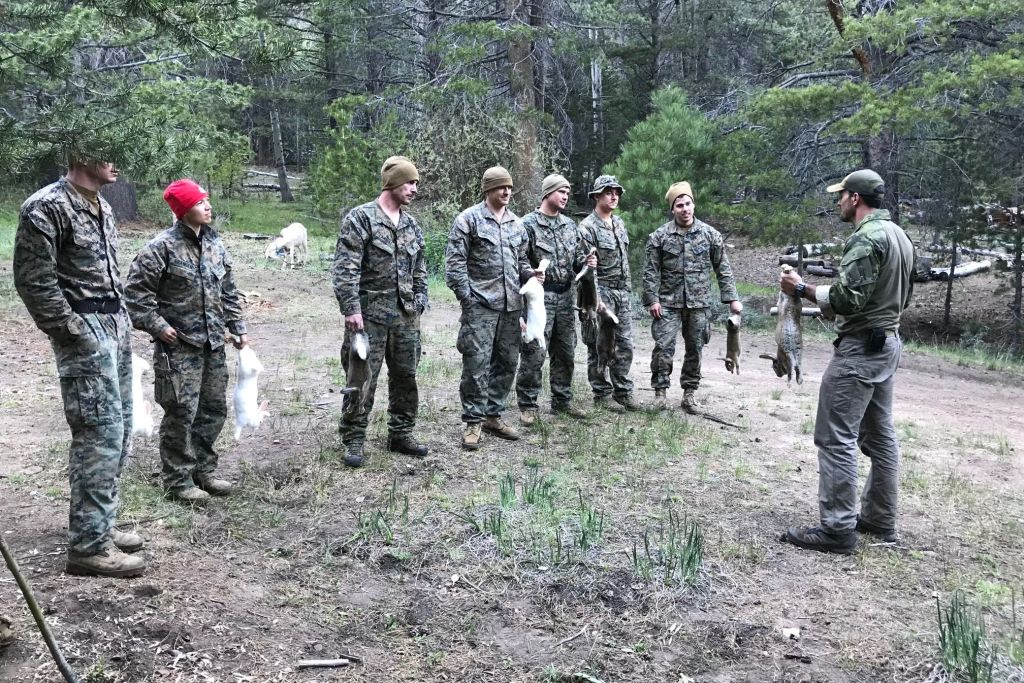 a group of people in the wilderness holding rabbits