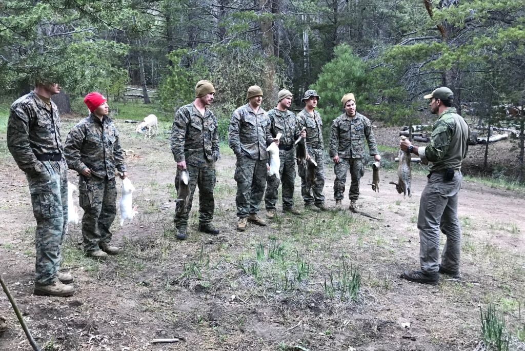 a group of people in the wilderness holding rabbits
