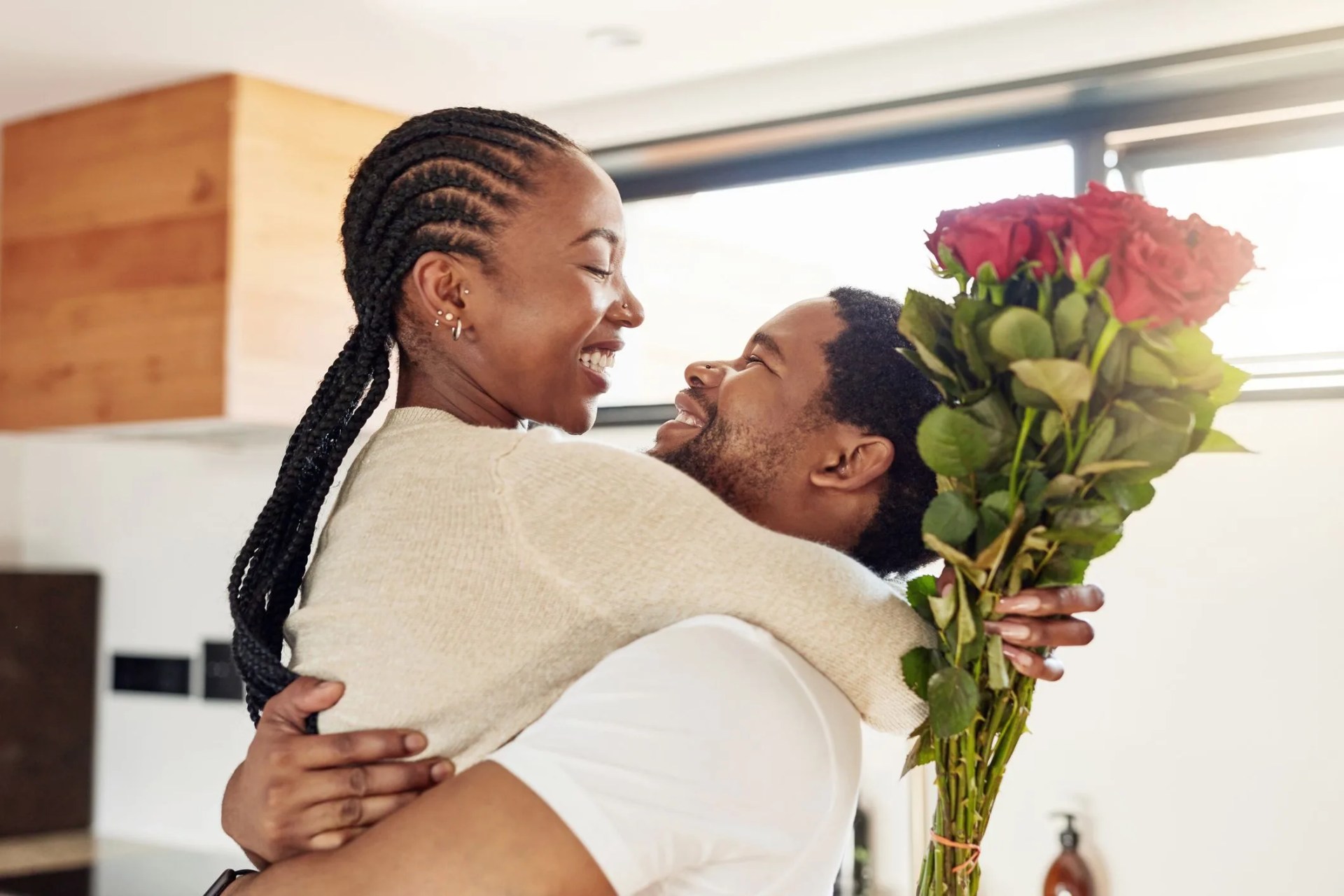 shot of a young man surprising his wife with a bunch of flowers at home