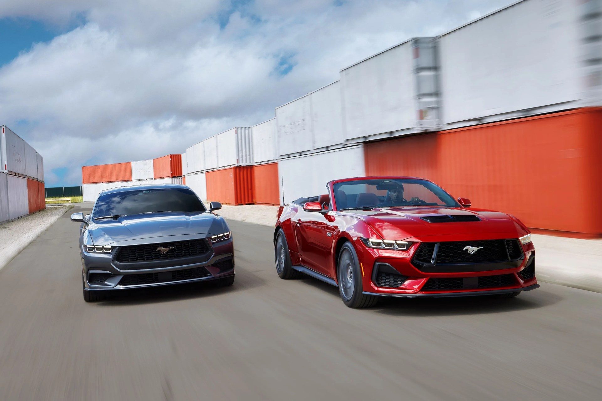 2024 ford mustangs racing in front of shipping containers