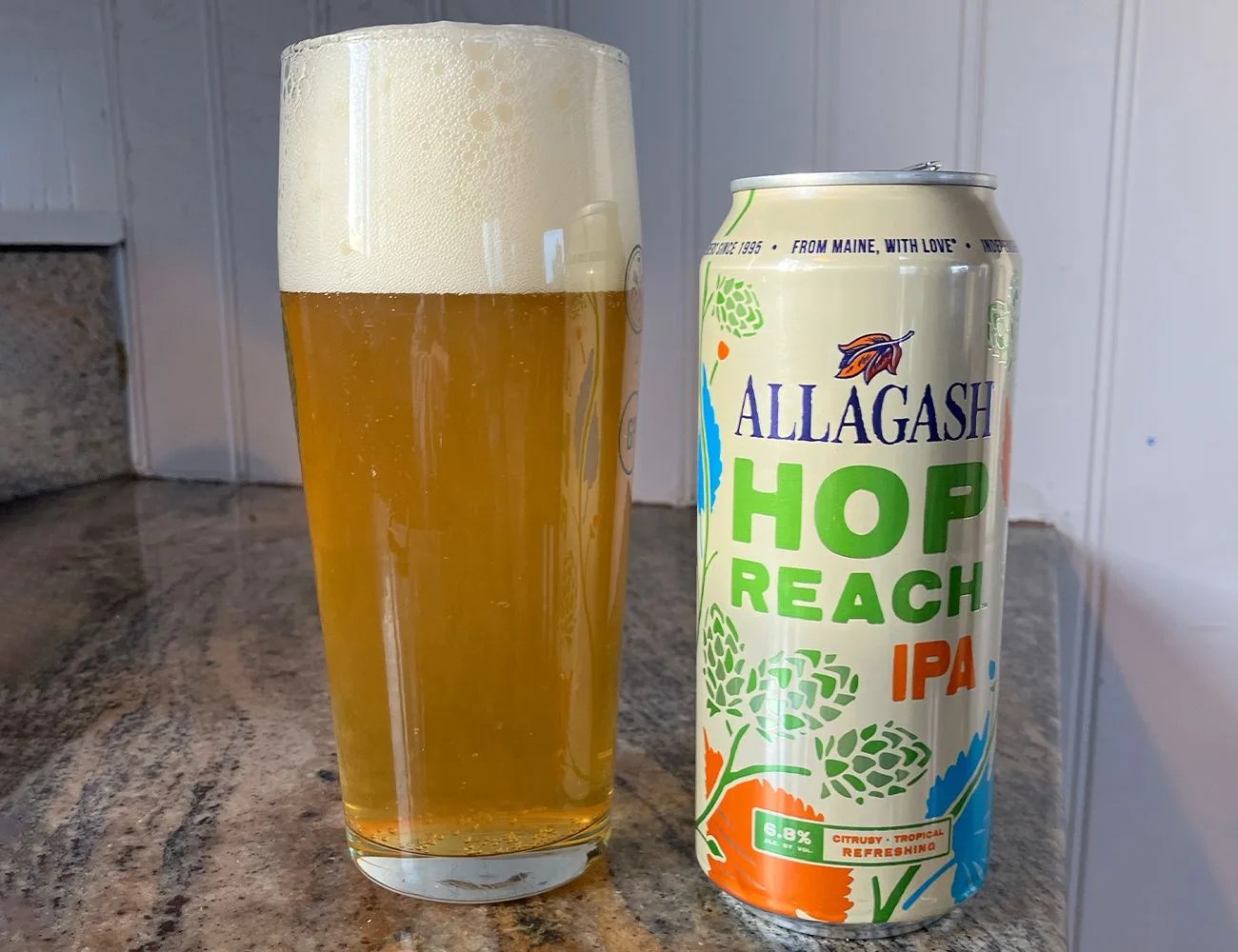 a glass of beer next to a can on a counter