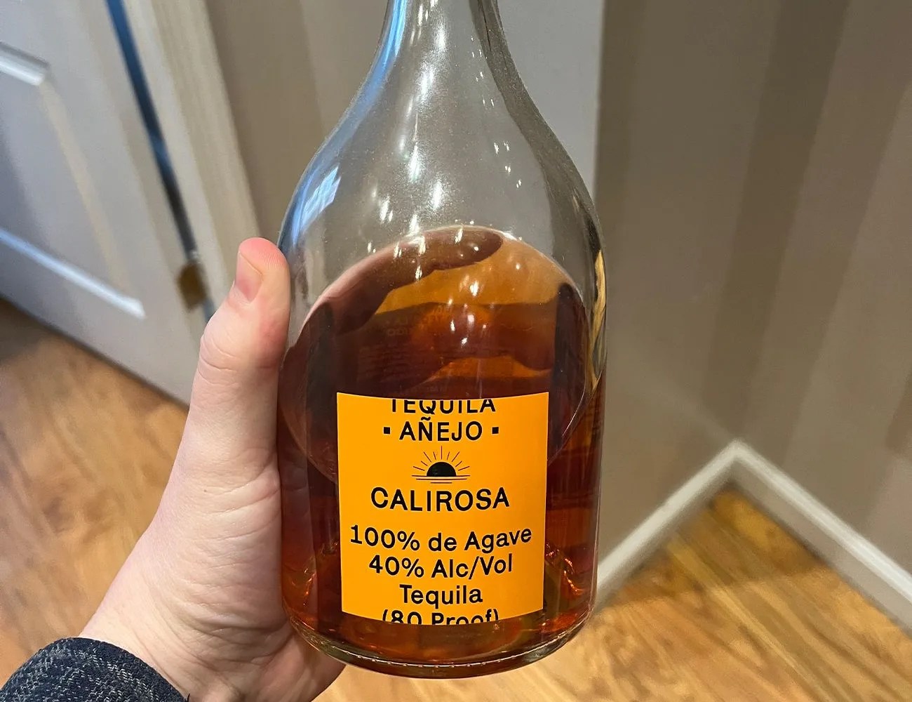 a hand holding a bottle of tequila