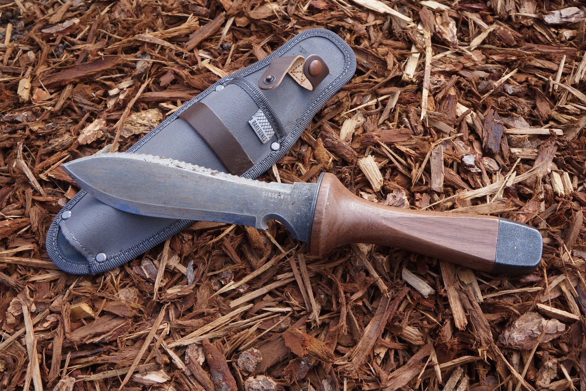 a garden knife and sheath on mulchy ground