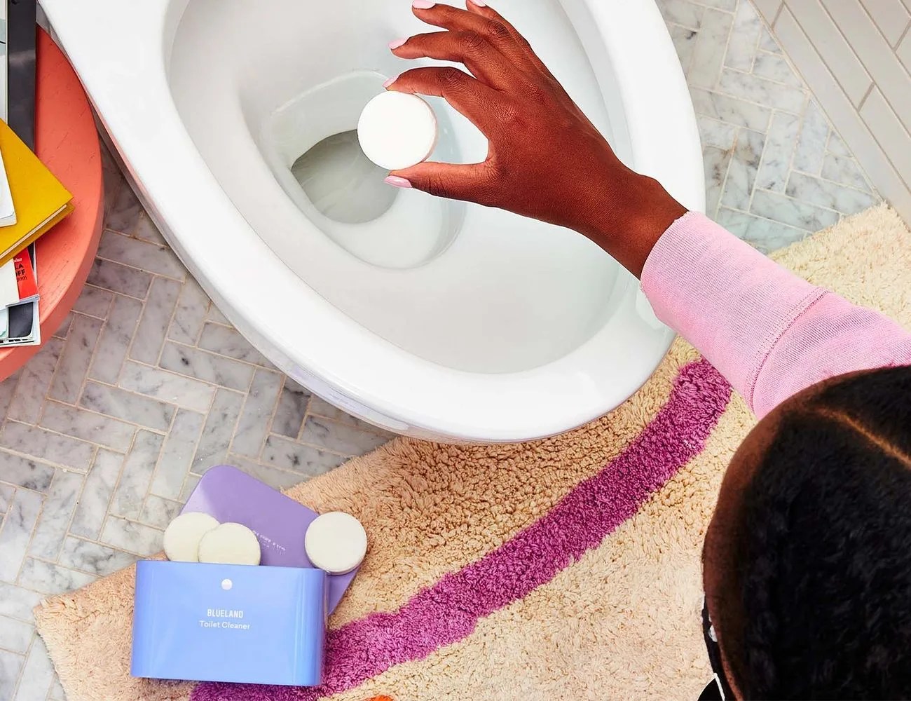 a person adding a cleaning tablet to a toilet bowl