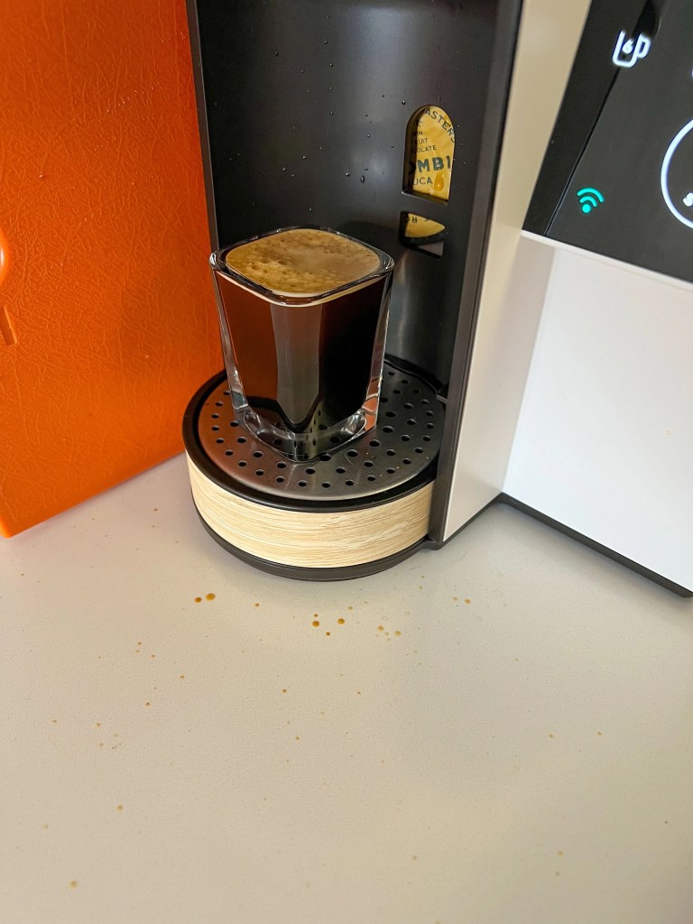 bruvi coffee maker with an espresso shot on a counter with coffee droplets
