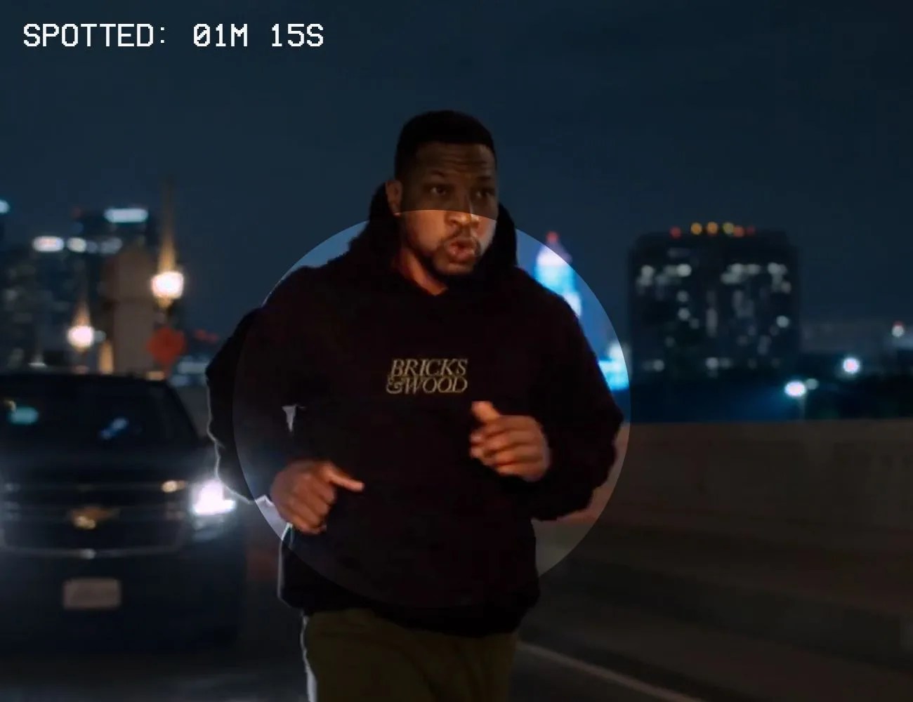 a man running down the street in a black hoodie that says bricks and wood