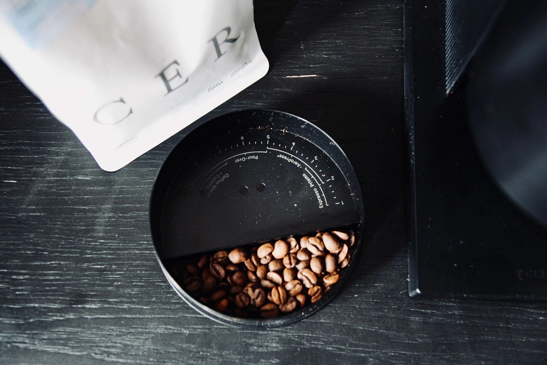 coffee beans in a fellow opus grinder on a counter next to a bag of coffee